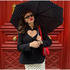 Outfit shot highlighting the waist-defining shape of a black short blazer paired with a midi skirt and mini shoulder bag for evening polish.