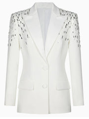 Close-up of sequin patchwork along the shoulder of a white tailored blazer, highlighting contrast and texture.