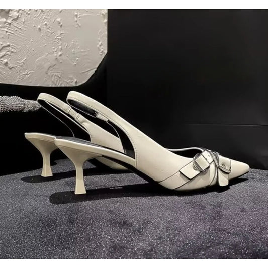 Pair of beige high-heeled shoes for formal party wear with a buckle on a textured surface.