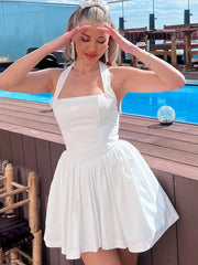 Woman in a white halter neck sleeveless mini dress with ruffles, spending time by a poolside.