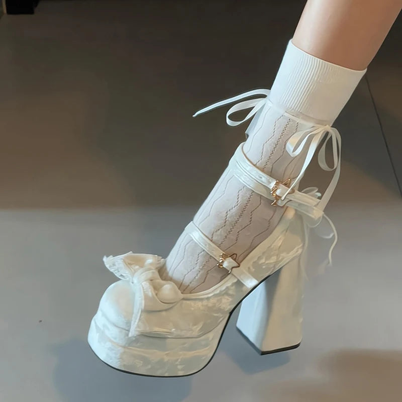 White platform Mary Jane bow pumps styled for a wedding, worn with white socks on a neutral background.
