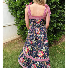 A woman wearing a wide-strap ankle-length sundress for relaxed summer days with a striped top in an outdoor setting.