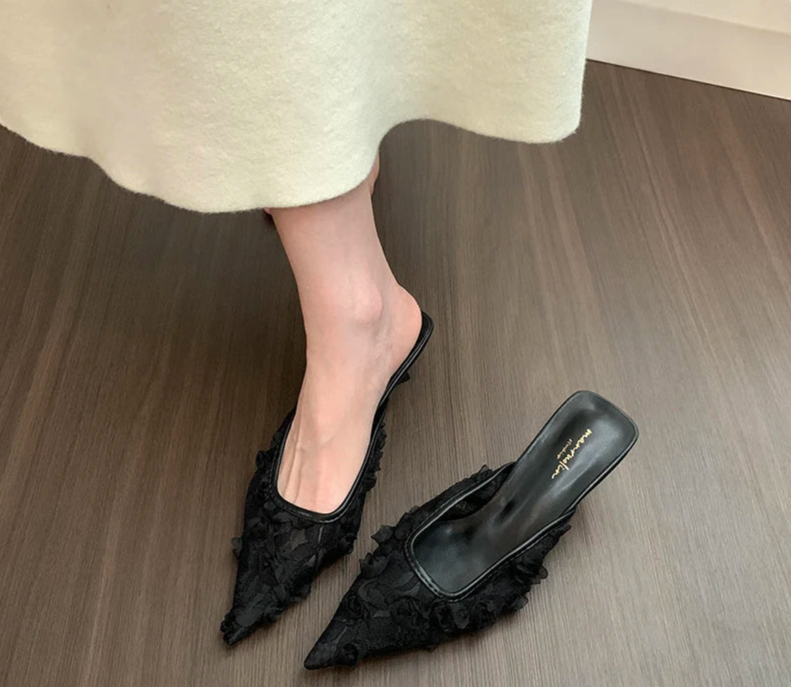 Close-up of floral lace detailing on black mule heels