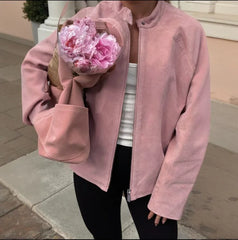 A person wearing a women’s soft suede outerwear zip fashion jacket for office and campus looks holding a bouquet of pink flowers.