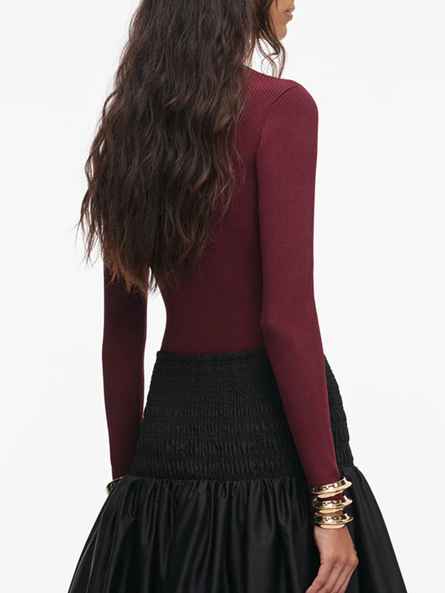 Long sleeve ribbed turtleneck knit top styled with a chain belt and skirt