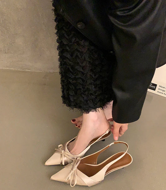 Close-up of butterfly-knot pointed-toe heels in satin finish