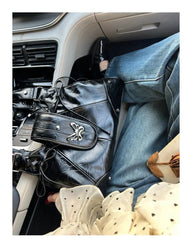 Y2K style black butterfly handbag on a car seat next to a person wearing jeans.