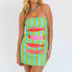 Woman wearing a strapless mini dress with bold fish graphic and Y2K stripes on a white background