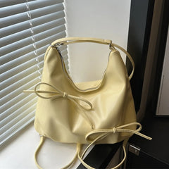 Yellow PU leather bucket bag with bow accents near window blinds