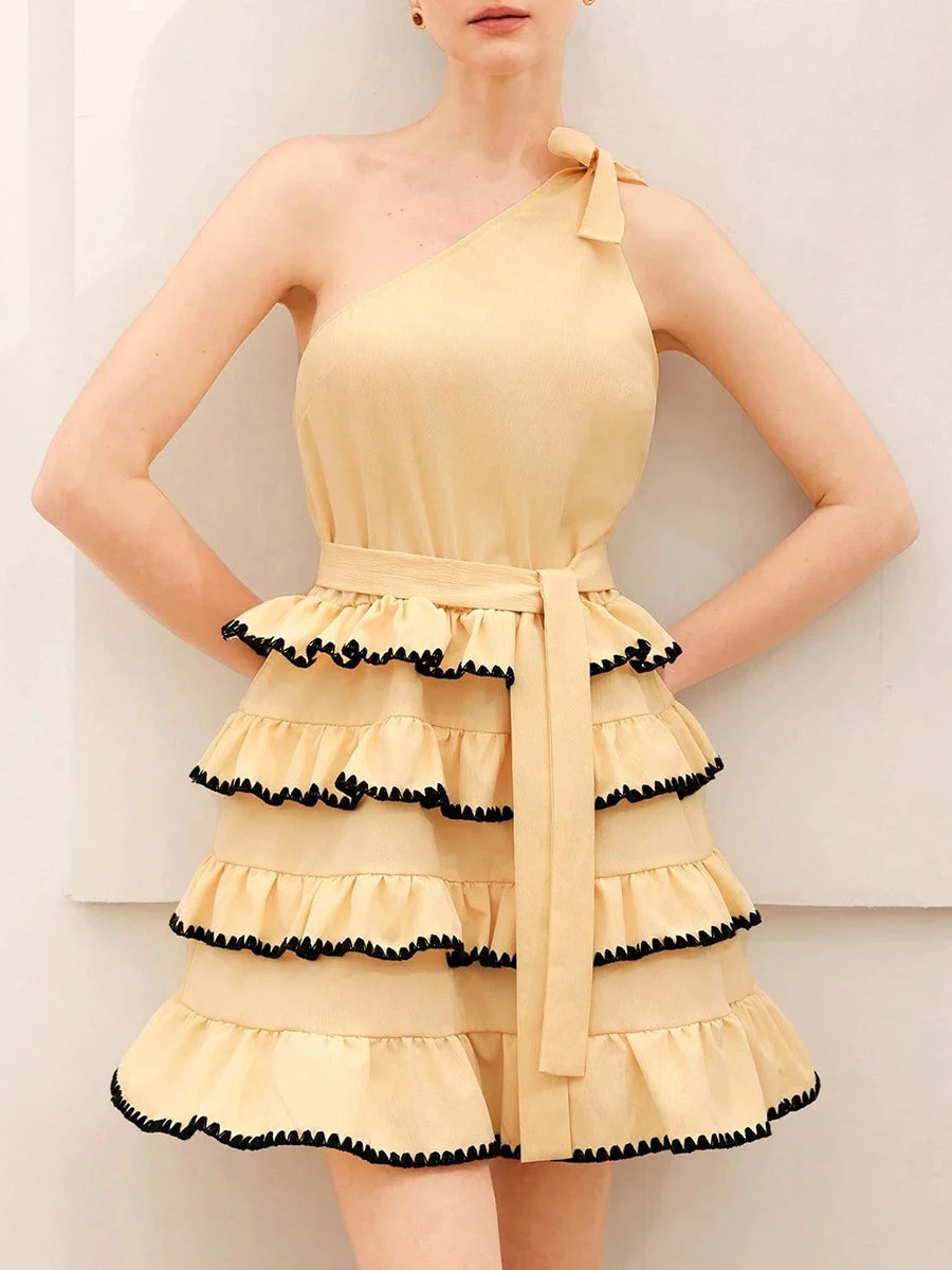 Yellow one-shoulder mini dress with layered ruffles and black trim on a plain background