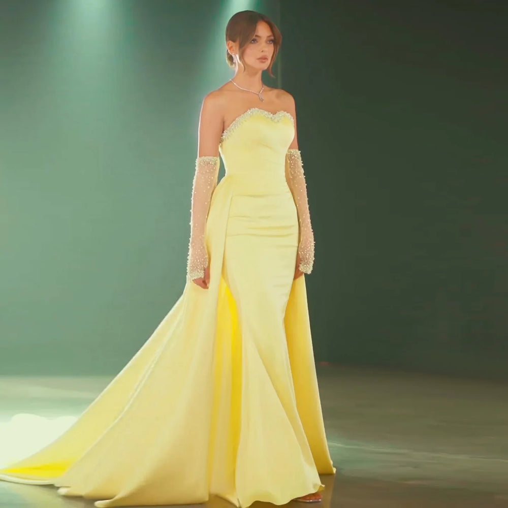 A woman wearing a yellow satin mermaid gown with a sweetheart neckline for a formal event.