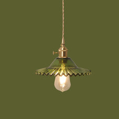 Vintage-style pendant light with green glass shade and brass fixture on a solid background