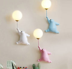 Golden Atelier LED wall lamp in the shape of a friendly cartoon bear, mounted on a wall in a child's room and casting a soft glow. Pink Whit Blue Bear