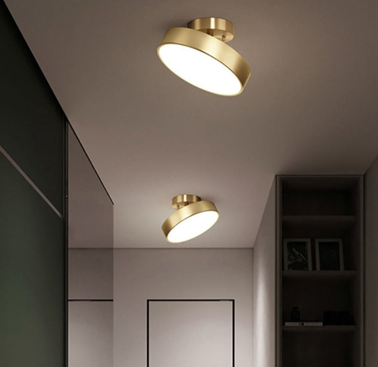 Modern round LED ceiling light with a copper finish and a warm glow, mounted on a recessed ceiling in a dark room.