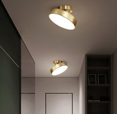 Modern round LED ceiling light with a copper finish and a warm glow, mounted on a recessed ceiling in a dark room.