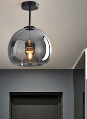 A pendant ceiling lights with dark glass balls and metallic halide bulbs hang over a room with dark walls and light-colored furniture.