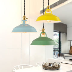 A collection of colorful hanging ceiling lampshades in various vibrant colors, including yellow, blue and green, against a neutral background with decorative items and plants over a dining table.