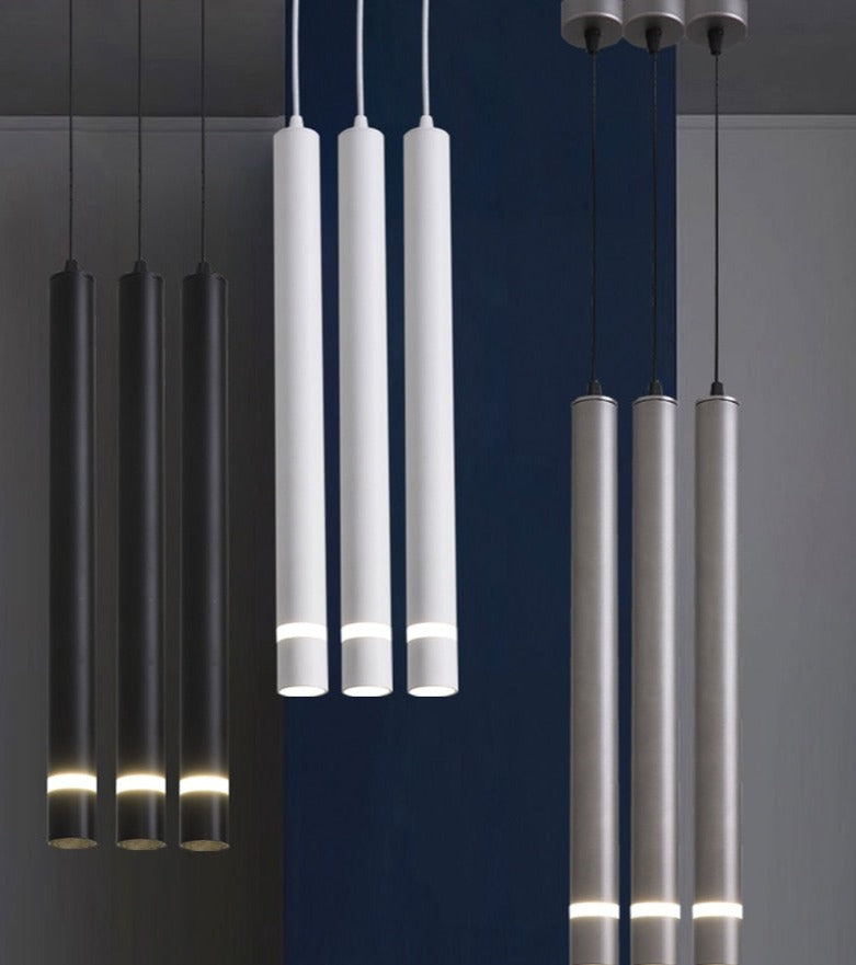 Three pendant tube lights with a modern style, featuring long cylindrical shapes in white, black, and grey colours, suspended from the ceiling.