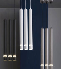 Three pendant tube lights with a modern style, featuring long cylindrical shapes in white, black, and grey colours, suspended from the ceiling.