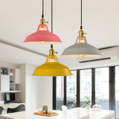 A collection of colorful hanging ceiling lampshades in various vibrant colors, including yellow, blue and pink, against a neutral background with decorative items and plants over a dining table.